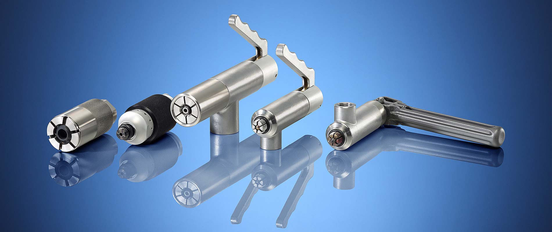 Schnellanschluesse Fünf verschiedene Werkzeuge aus Metall auf einem blauen Hintergrund. Die Werkzeuge haben unterschiedliche Formen und Größen, die eine Verbindung zu präzisen mechanischen Anwendungen suggerieren.